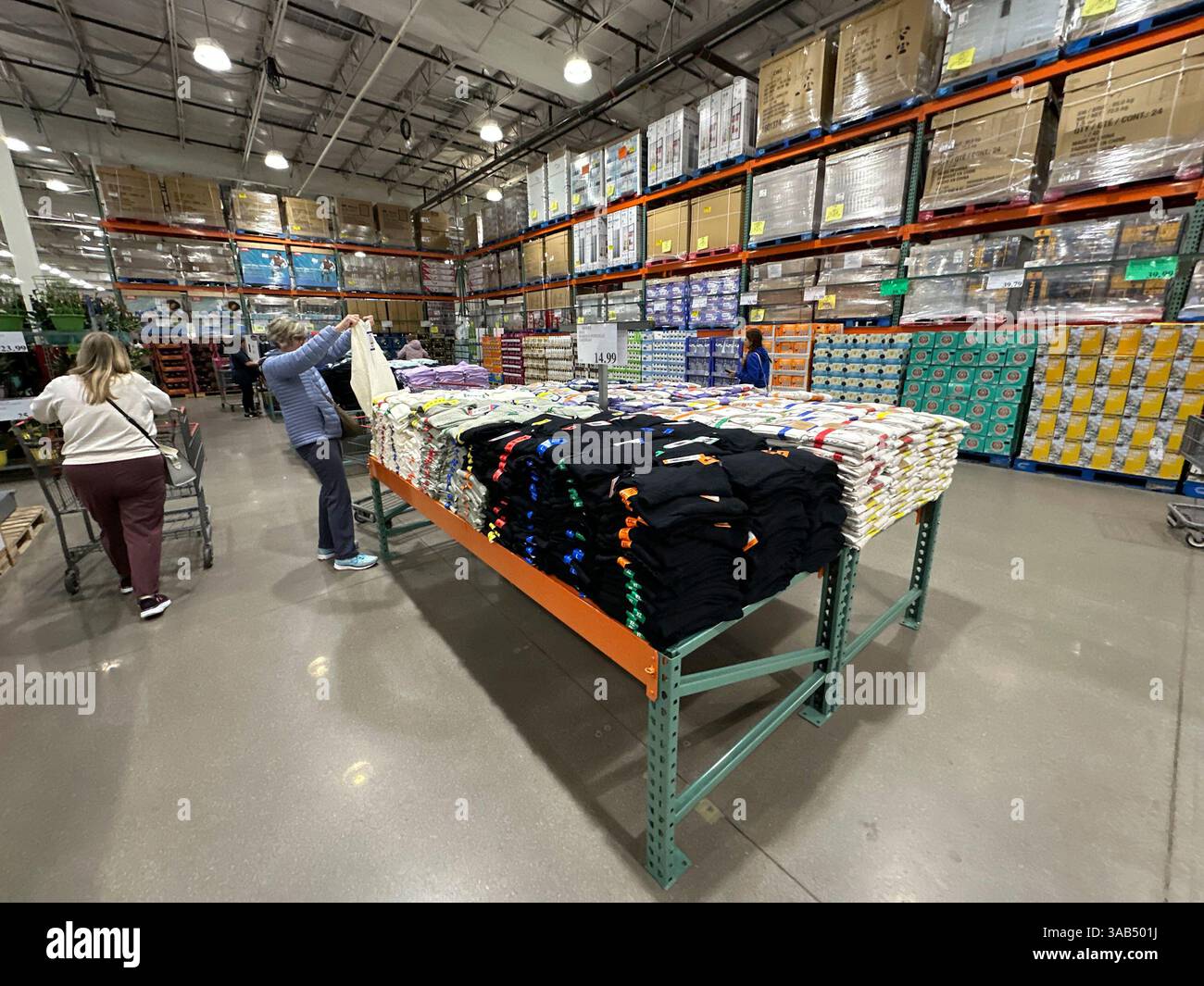 Shoppers consider items of clothing on display on tables in a Costco ...