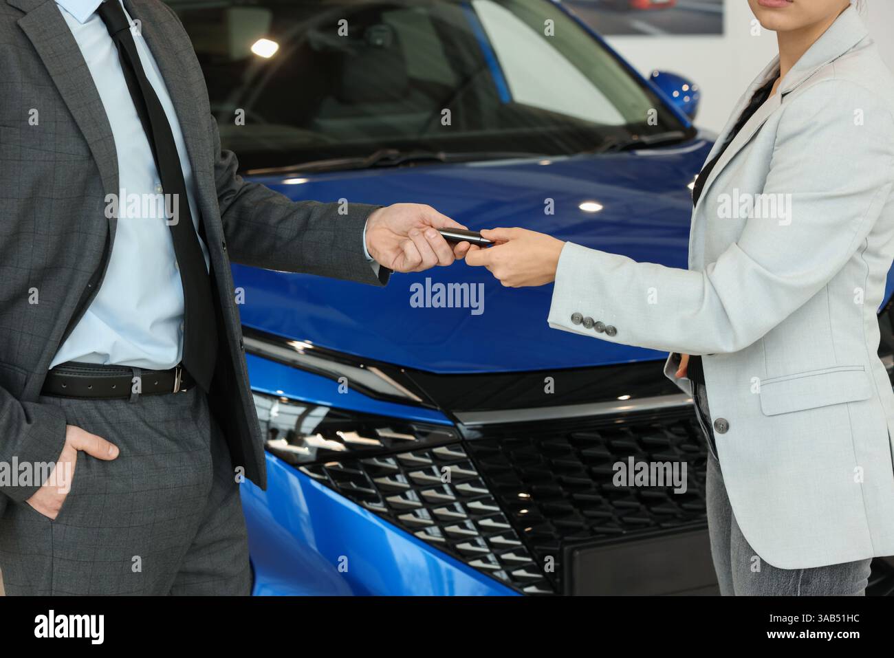 Salesman giving key to client near new car in salon, closeup Stock ...
