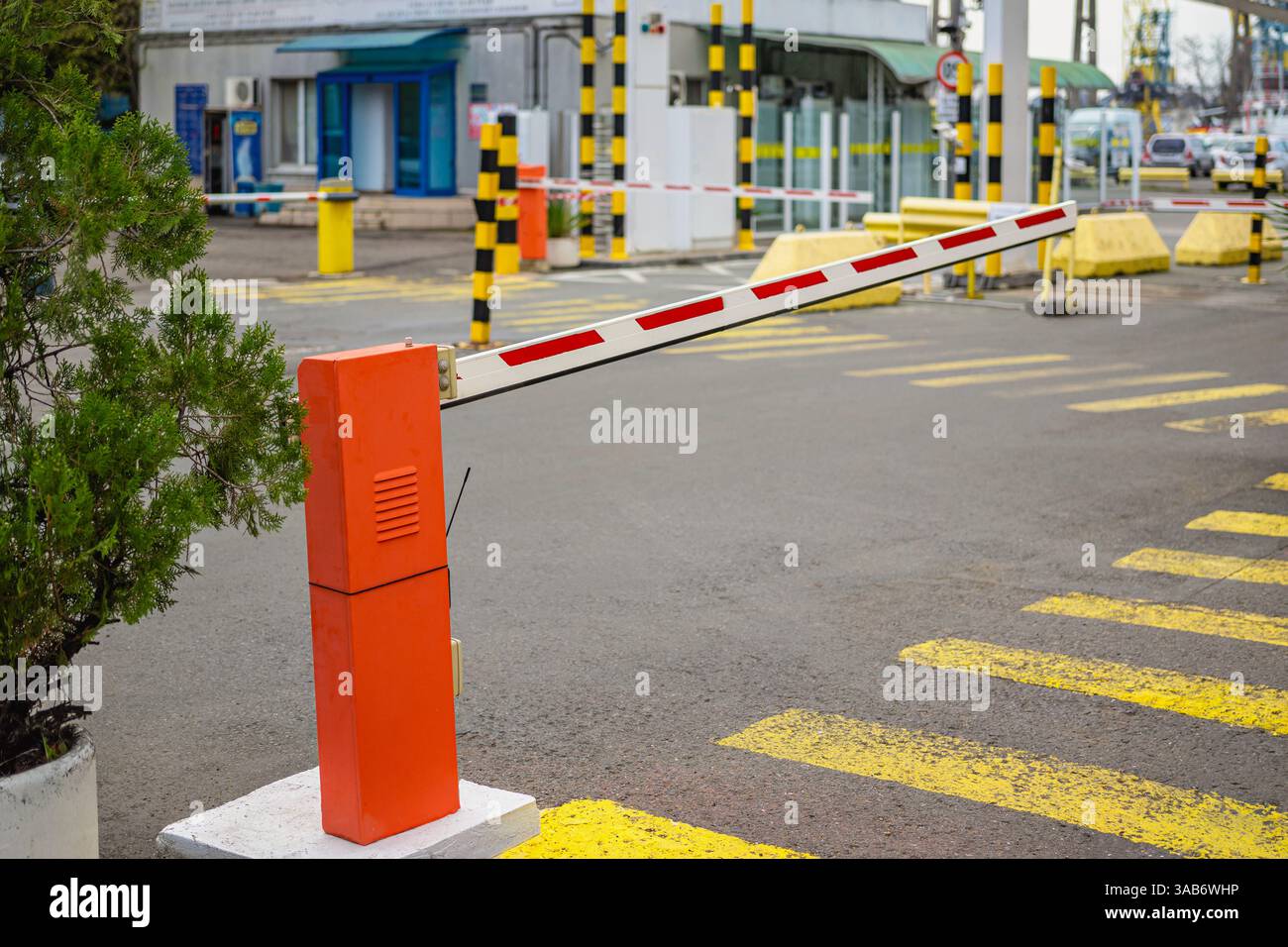 Orange automated barrier gate raised at parking area entrance with road ...