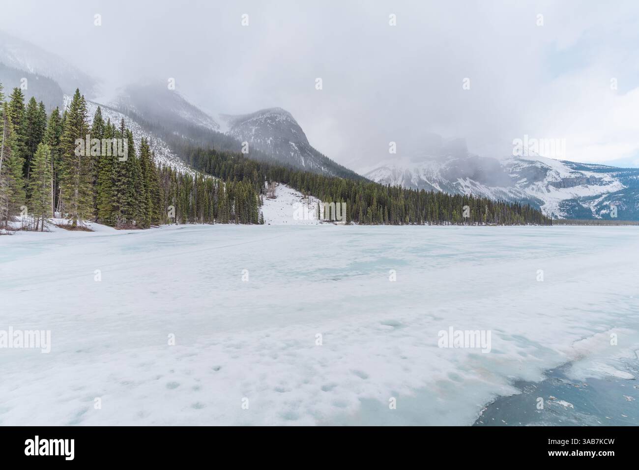 A serene frozen river winding through a valley of snow-covered ...