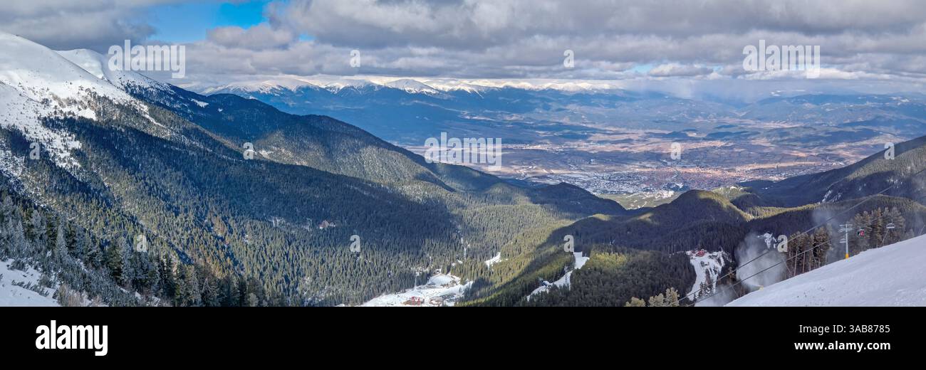 Panoramic view to the beautiful town of Bansko seen behind the evergreen forest and mountain hills at the horizon - Smartphone Captured Stock Image