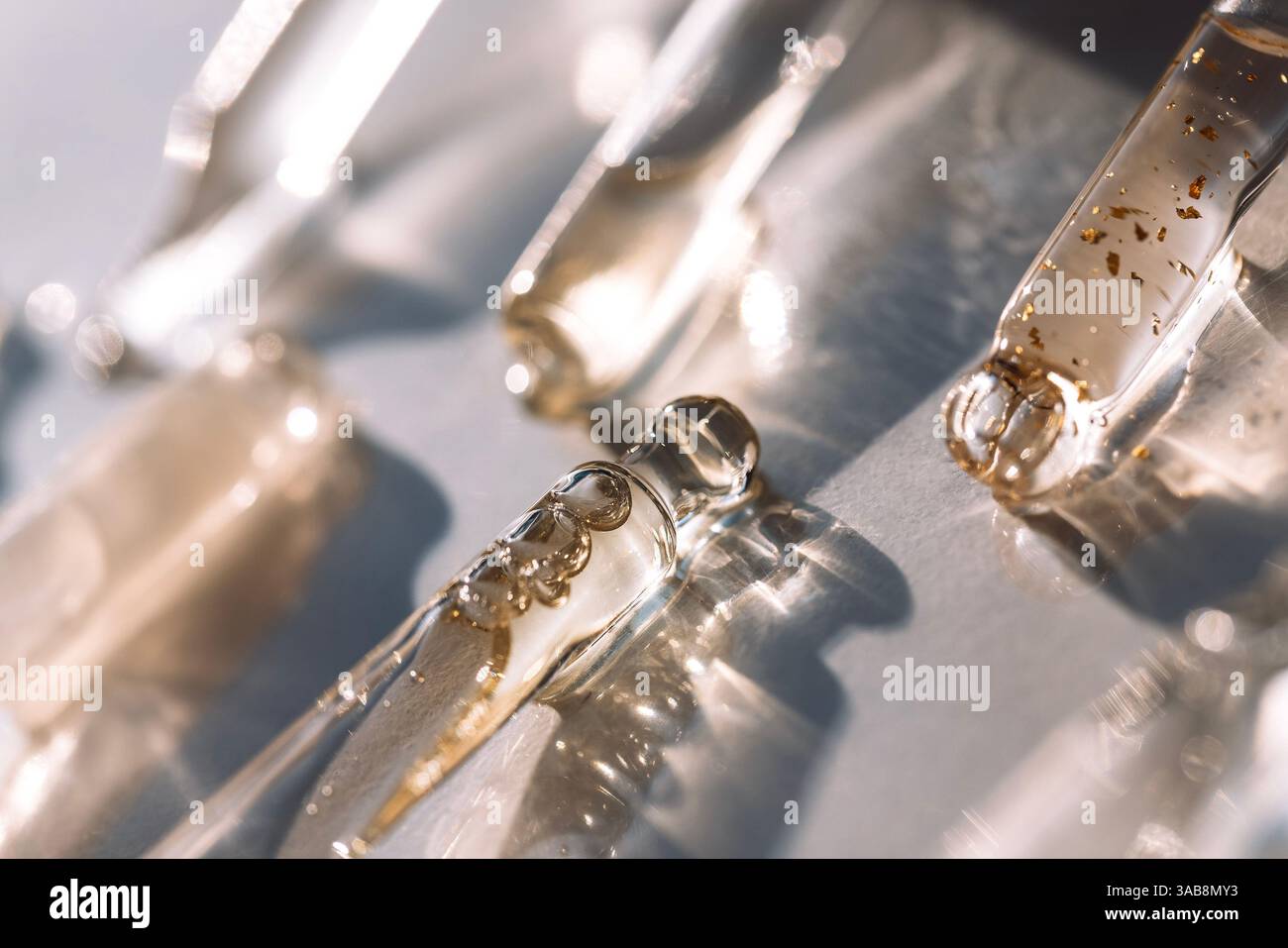 Close-up of glass pipettes with moisturizing serum with colloidal gold. Droppers with toning essence for facial skin with transparent drops on a white Stock Photo