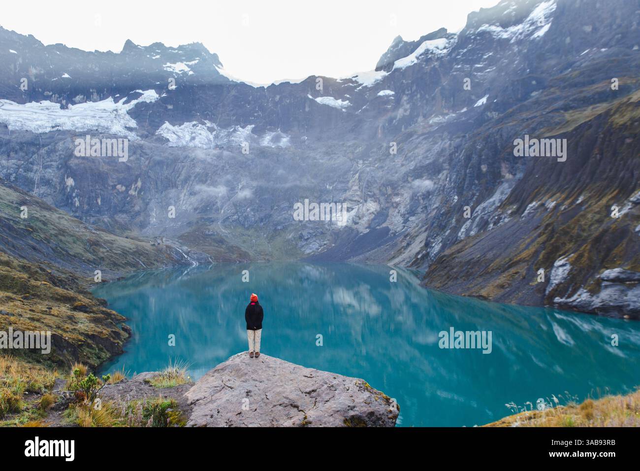 An Ecuadorian woman stands on a rocky ledge, overlooking the serene ...