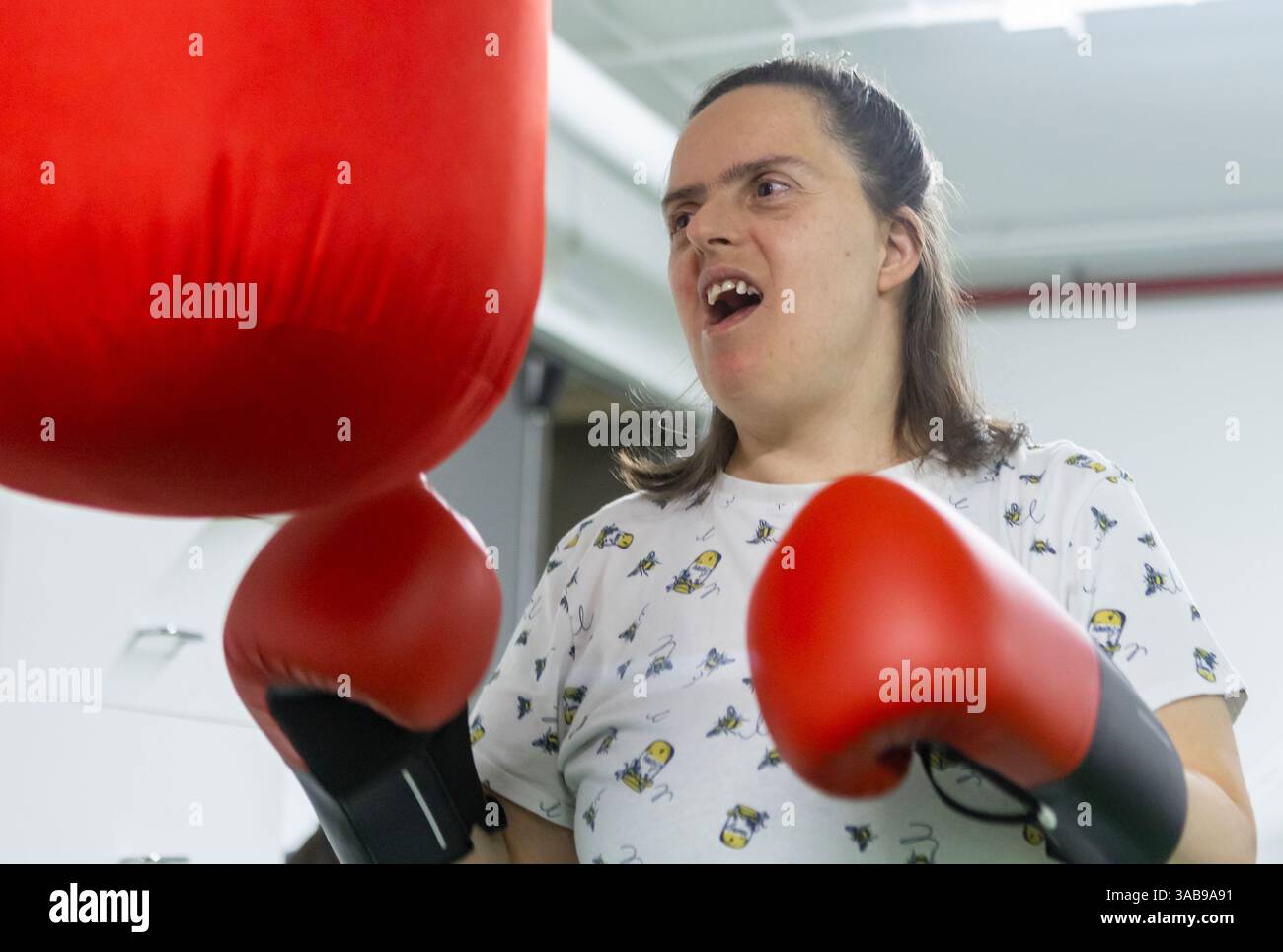 A woman enthusiastically punches a red boxing bag at a mental health ...