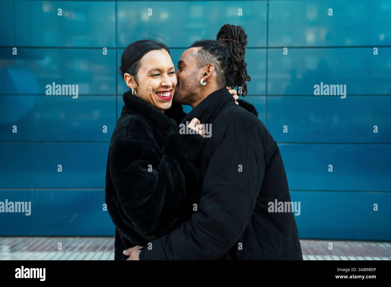 A happy multicultural couple enjoys a tender moment outdoors, embracing love and diversity. The duo's attire blends modern style with traditional allu Stock Photo