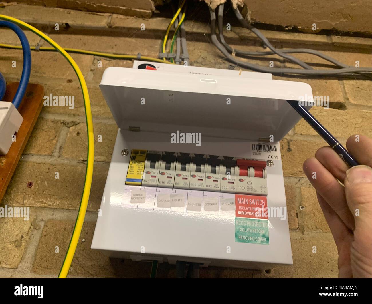 mains unit box electric fitted on a  wall new circuits type earth wire wired clipped cables metal surge protection mains switch British UK English l - Smartphone Captured Stock Image
