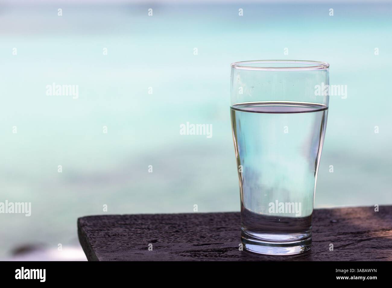 A glass of crystal clear water placed on a smooth surface under soft natural light Stock Photo