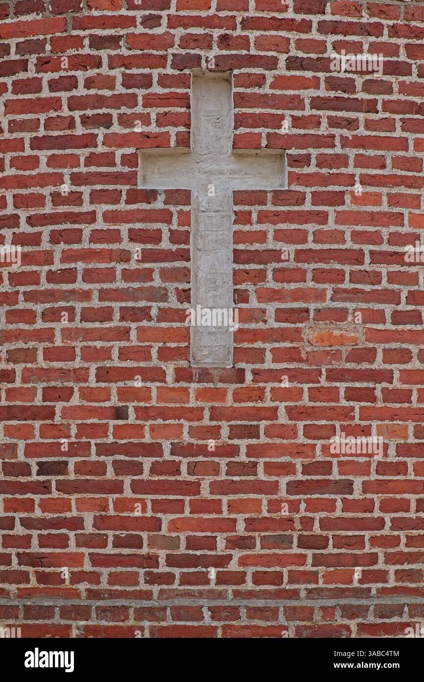 A white cross made into red brick wall. Stock Photo
