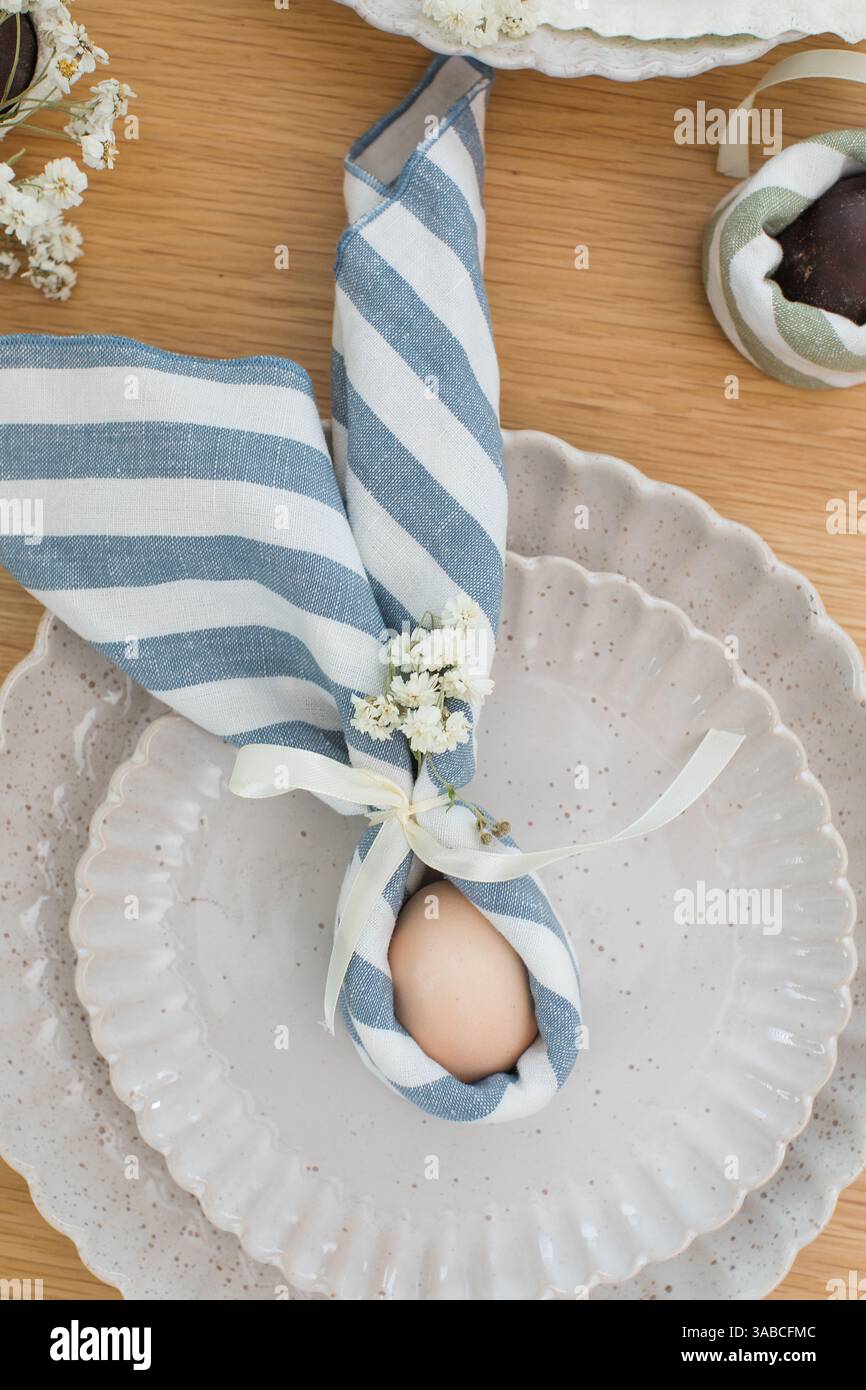 Easter egg wrapped in linen napkin in the shape of bunny with ears. Happy Easter  Stock Photo