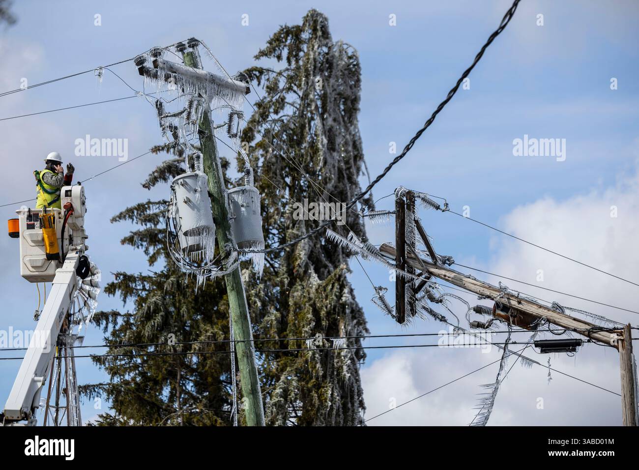 Crews work to restore ice-covered power lines and broken utility poles ...