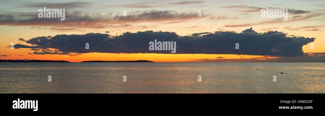 Long big dark cloud over the sea at sunset Stock Photo - Alamy