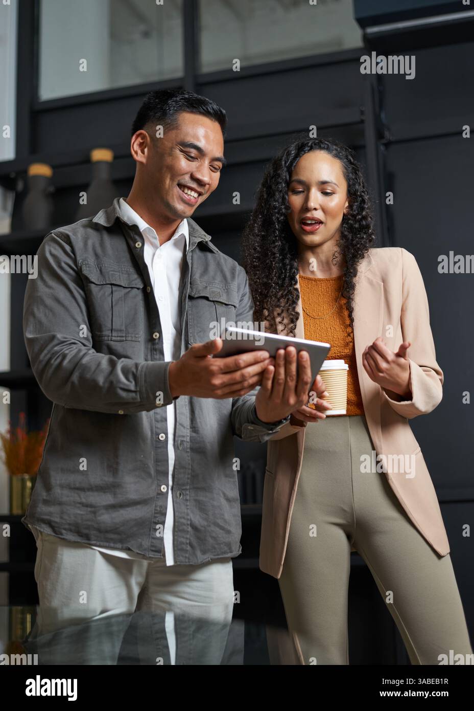 Two Professionals Collaborating in a Modern Office Environment While Reviewing a Digital Tablet Stock Photo