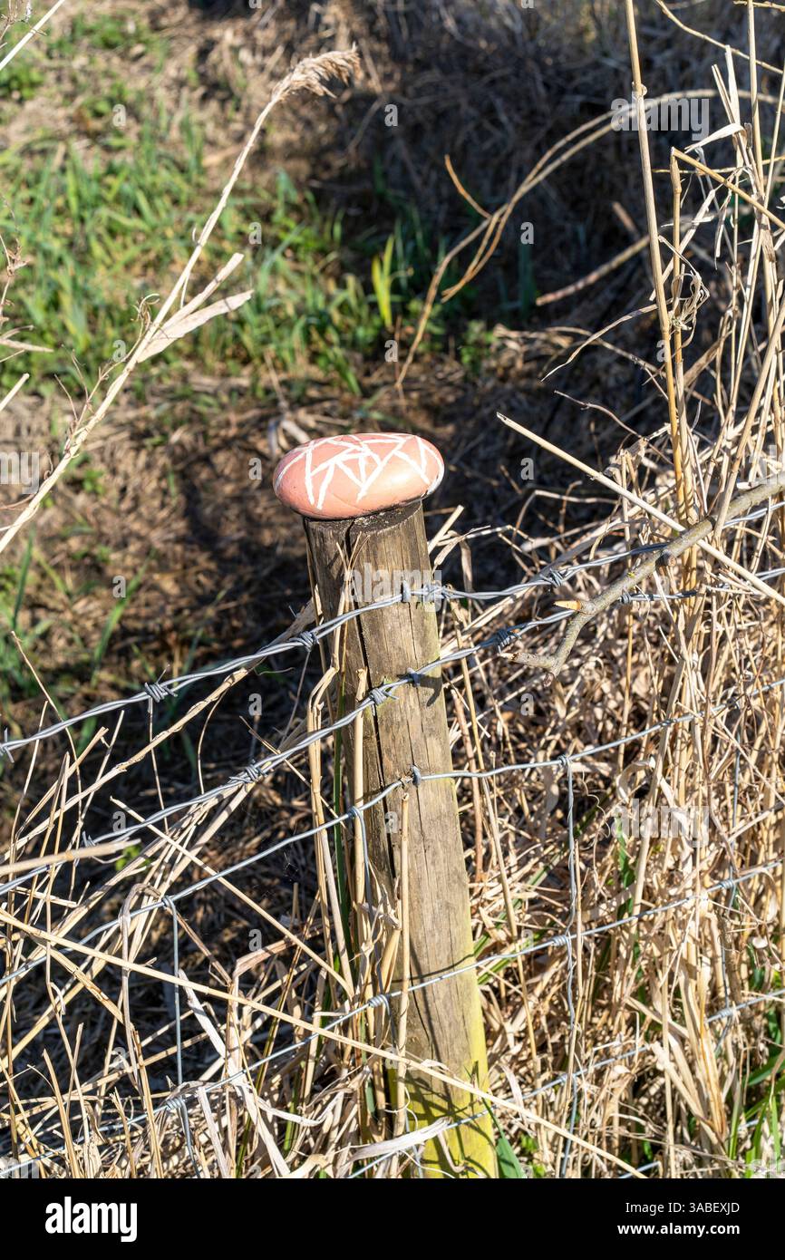 Large painted stone pebble on top of a fence post Stock Photo