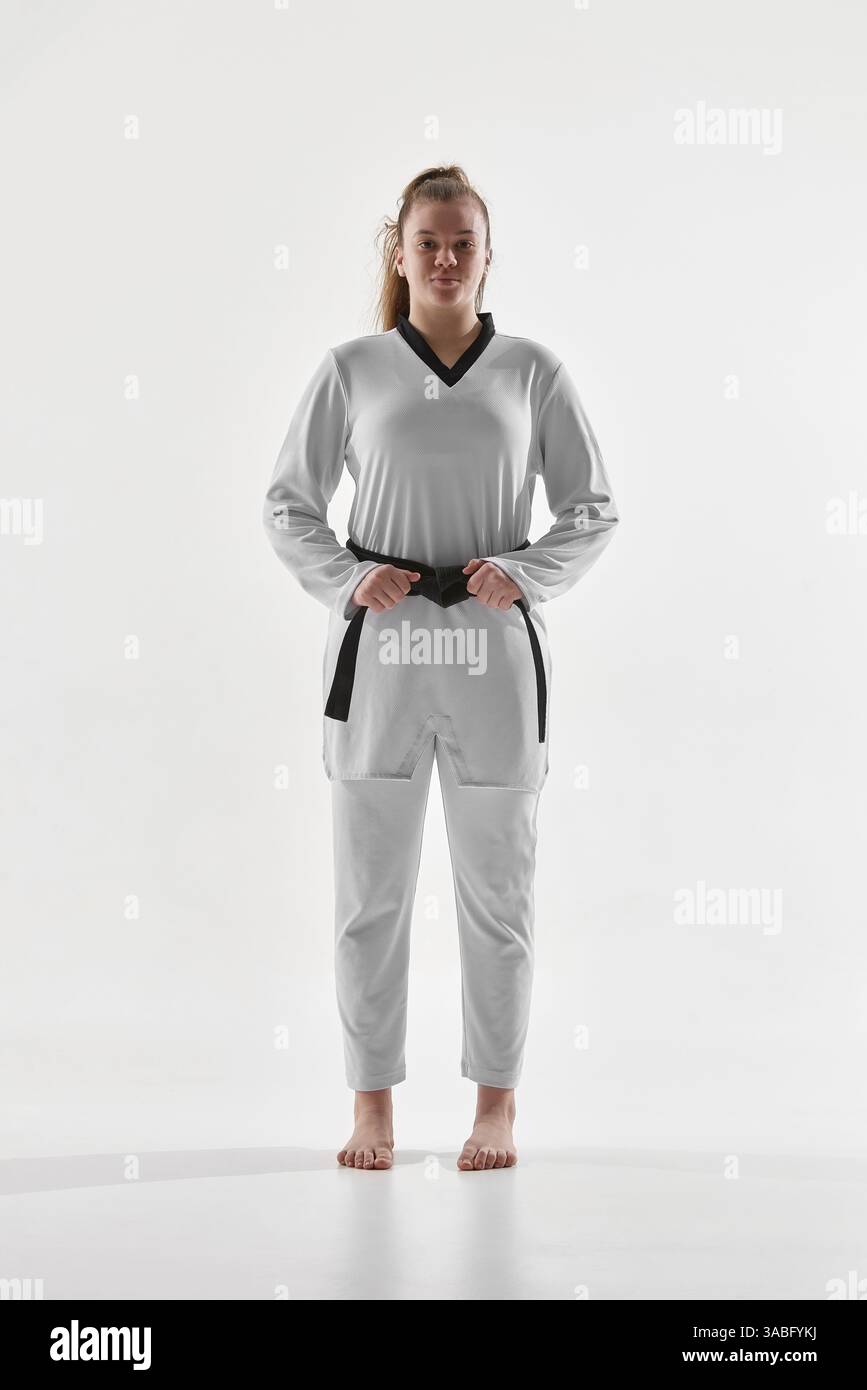 Female taekwondo athlete standing barefoot in white uniform with hands ...