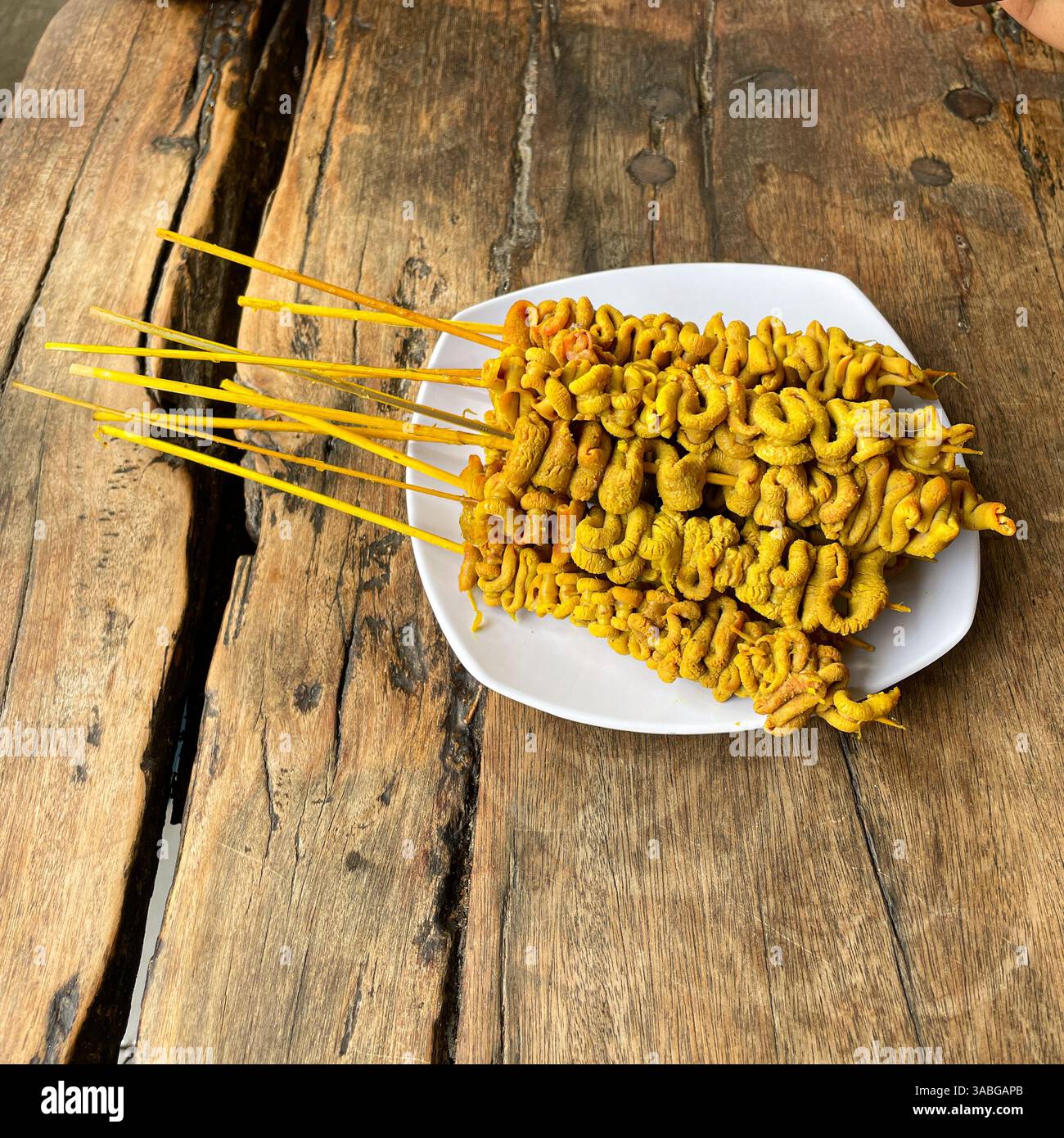 sate usus ayam Chicken Intestine Satay Served on white plate Usually Eat as Chicken Porridge Topping - Smartphone Captured Stock Image