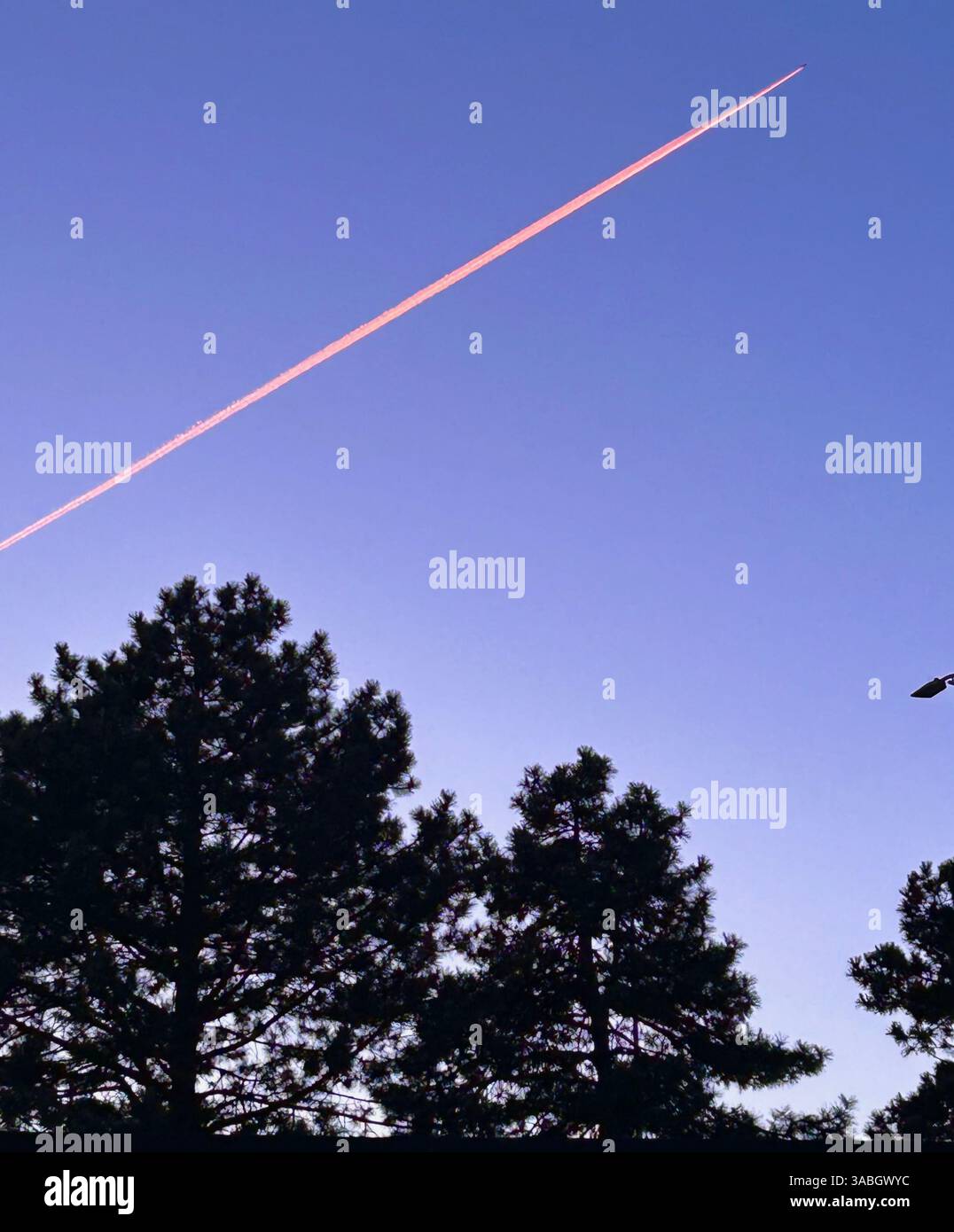 Jet soaring through the sky, leaving a vibrant pink smoke trail against a clear backdrop. - Smartphone Captured Stock Image