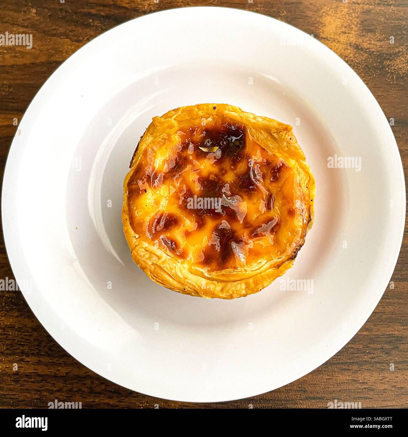 egg tart served on white plate over wooden table, top view - Smartphone Captured Stock Image