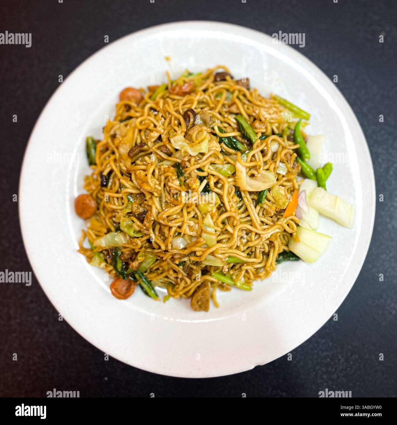 Stir-Fry Noodles with vegetables and pickle served on white plate and black background - Smartphone Captured Stock Image