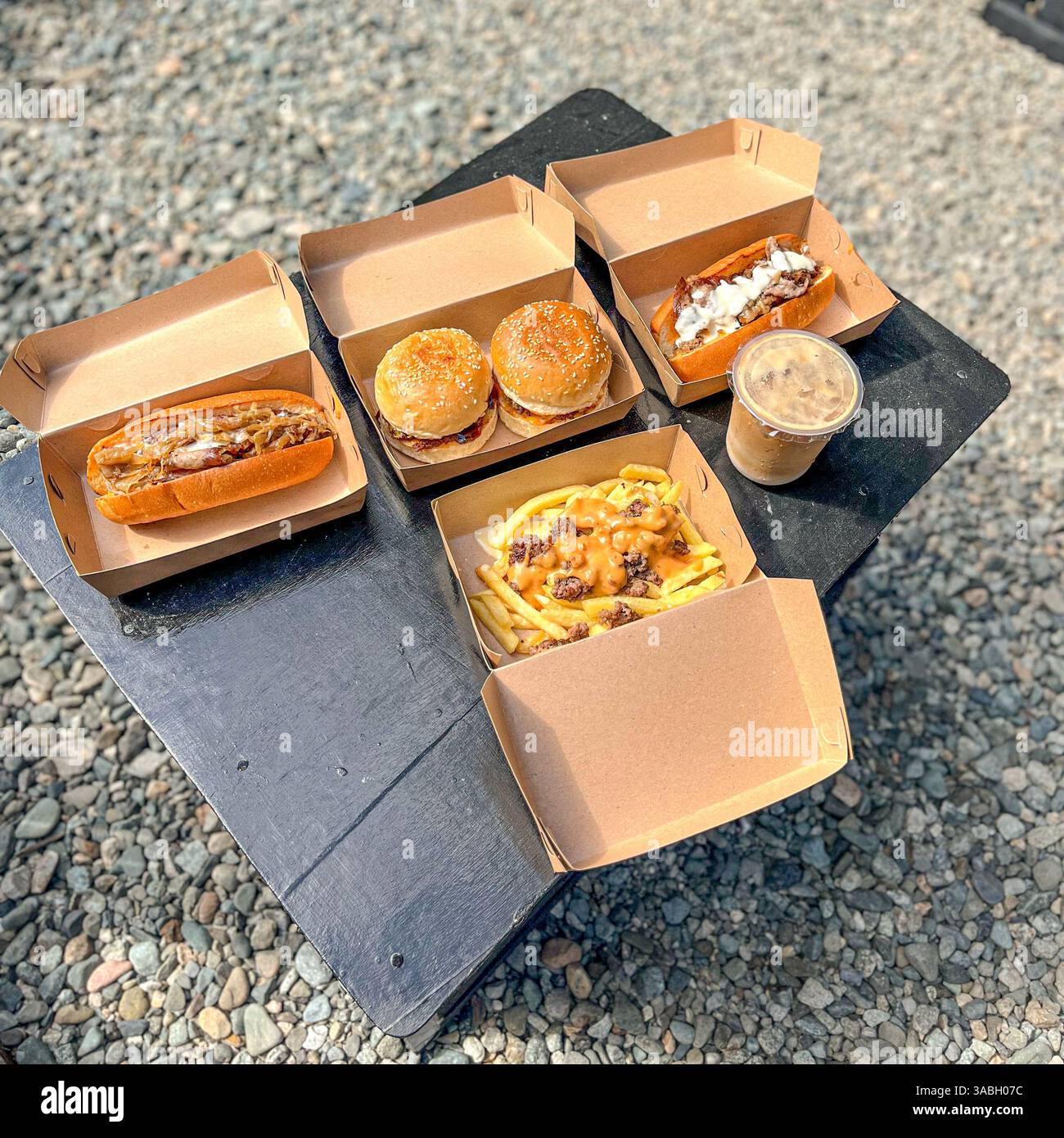 Delicious Beef Burger , Hot Dog, fries and iced coffee displayed on table top at food festivals - Smartphone Captured Stock Image