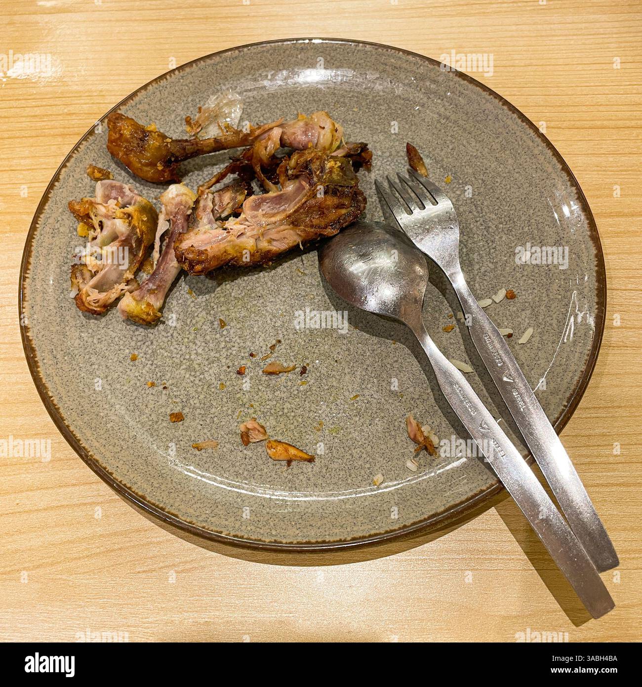 used dinner plates with spoons, forks and the remains of used chicken bones - Smartphone Captured Stock Image