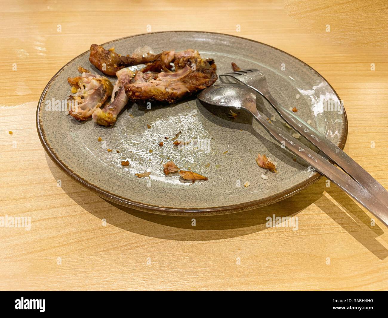 used dinner plates with spoons, forks and the remains of used chicken bones - Smartphone Captured Stock Image