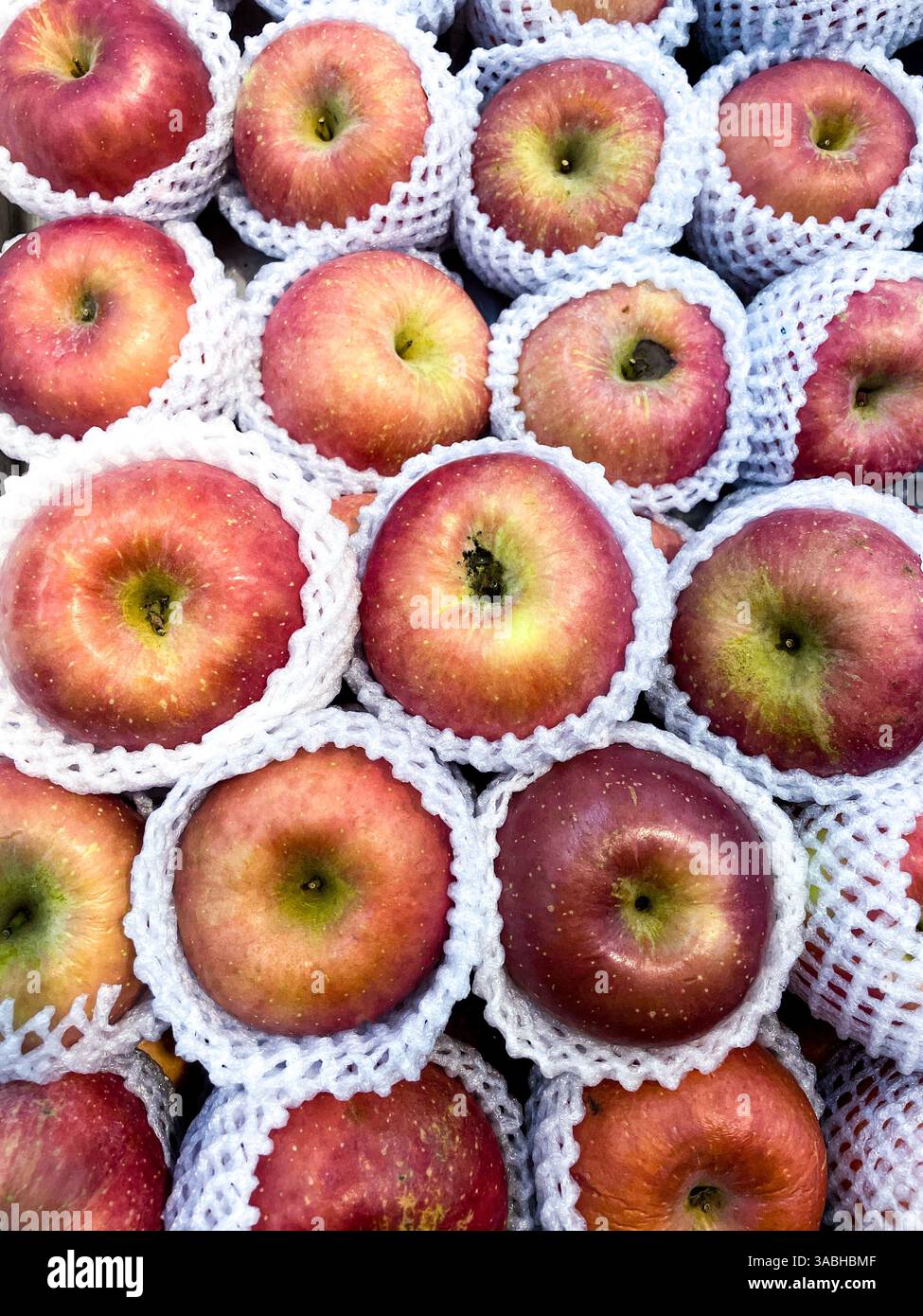 Fresh red apples wrapped in tempting fruit nets are in boxes being sold at traditional markets - Smartphone Captured Stock Image