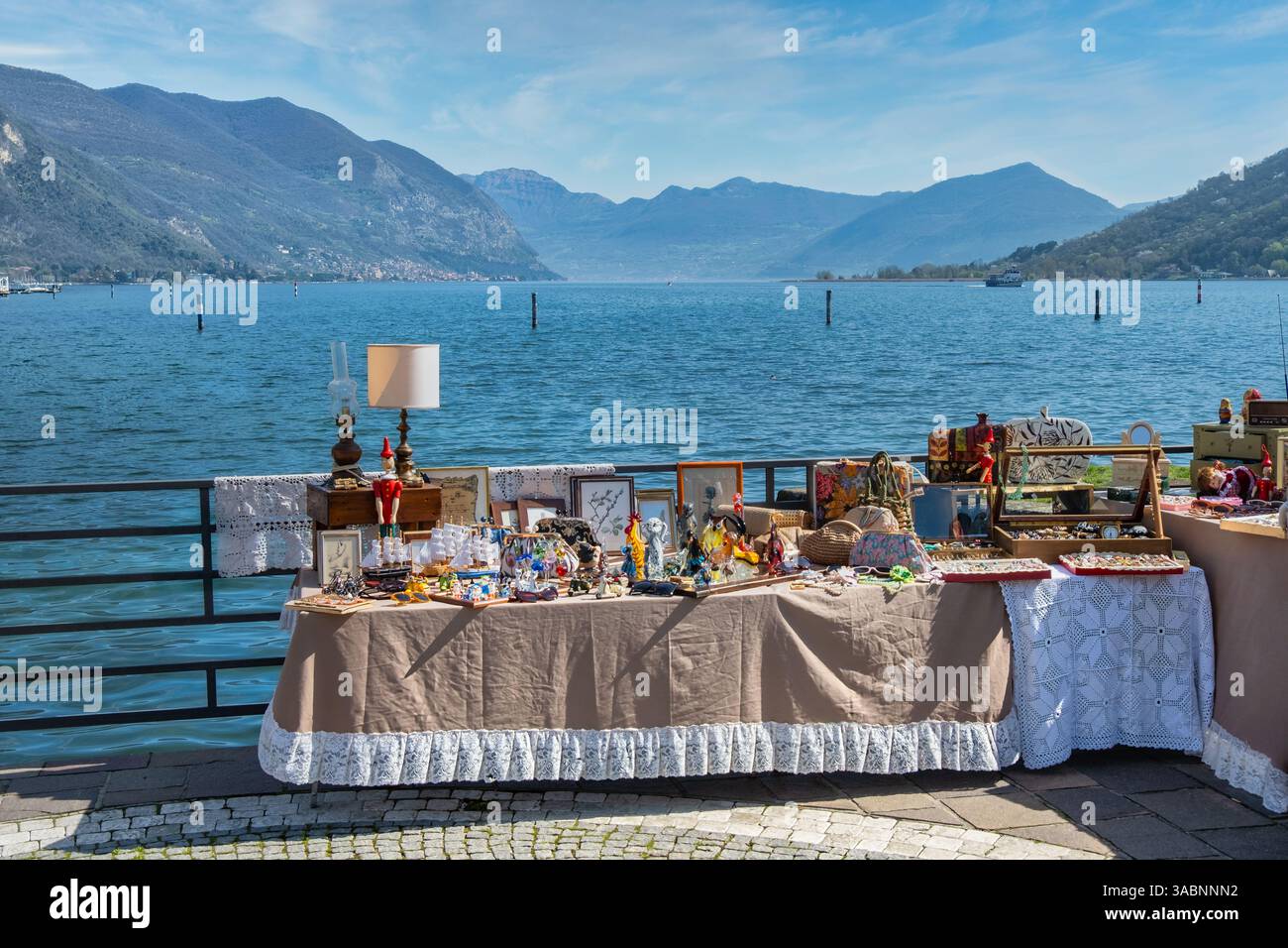 Scenic Antique Market by Lake Iseo, Italy – Vintage Handicrafts and Collectibles with Stunning Alpine Landscape, Tranquil Waters, and Picturesque Moun Stock Photo
