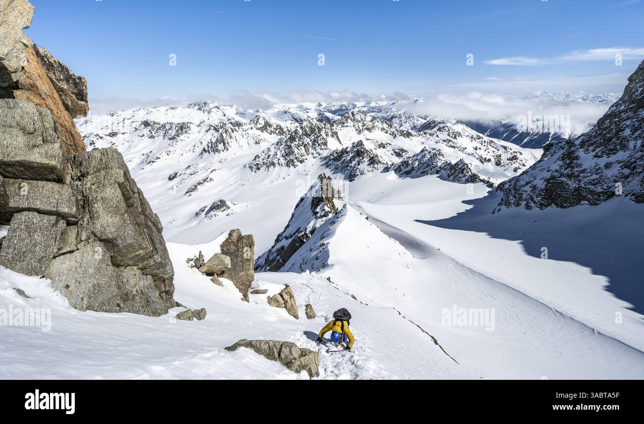 Mountaineer with ice axe and crampons, ascent through steep snowfield to Piz Kesch or Piz d'Es-cha in winter, view of mountain panorama with Vadret da Stock Photo