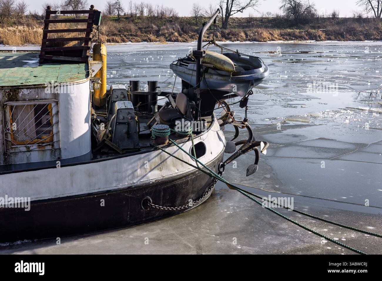 The stern of a river barge with rigging and ropes thrown over the pier ...