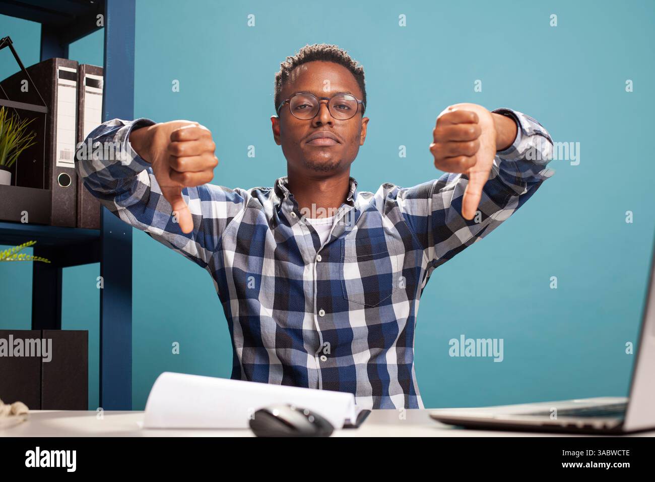 Closeup of black man giving two thumbs down towards camera, expressing ...