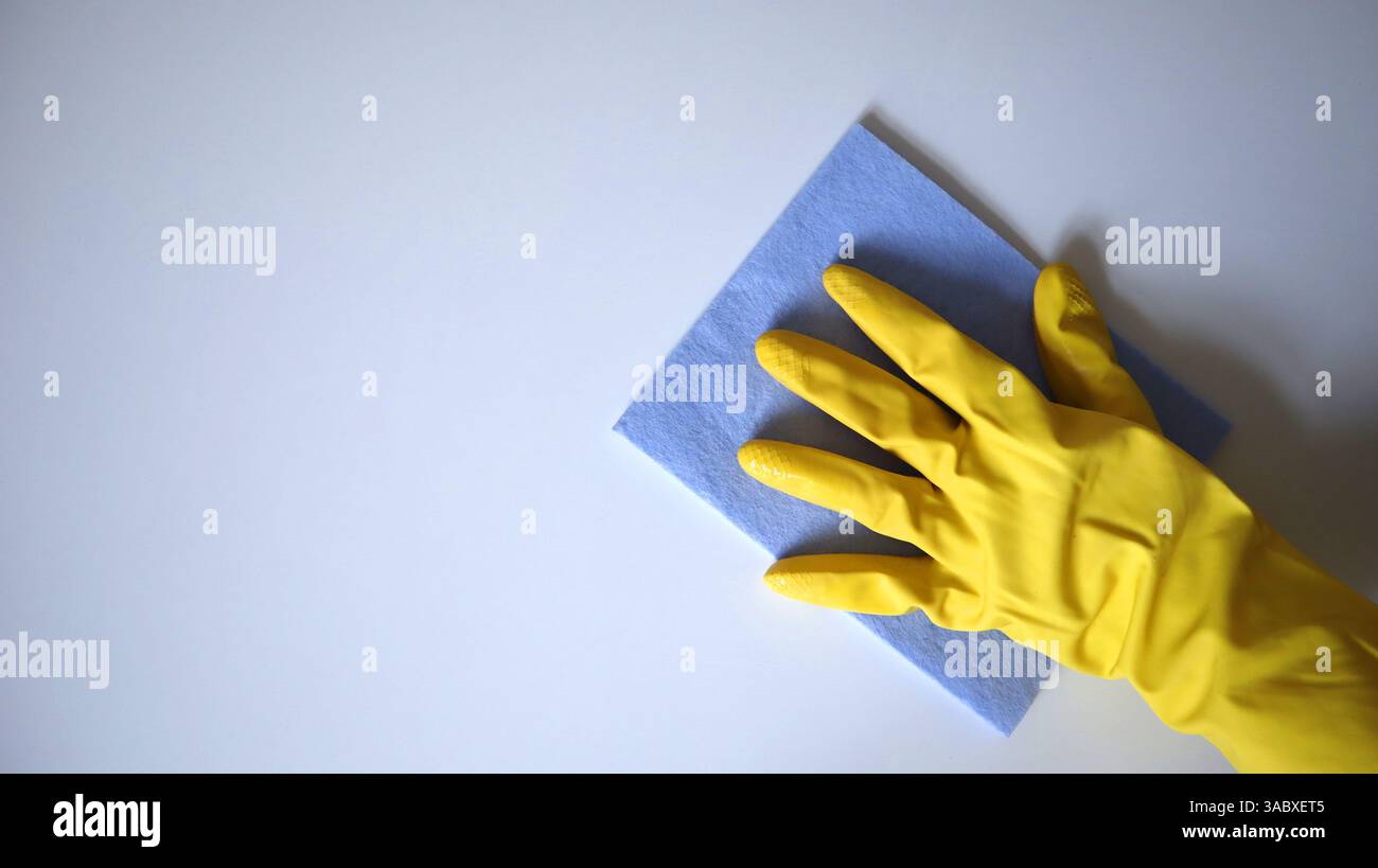 Photo of cleaning process. Hand in a rubber glove wiping a surface with ...