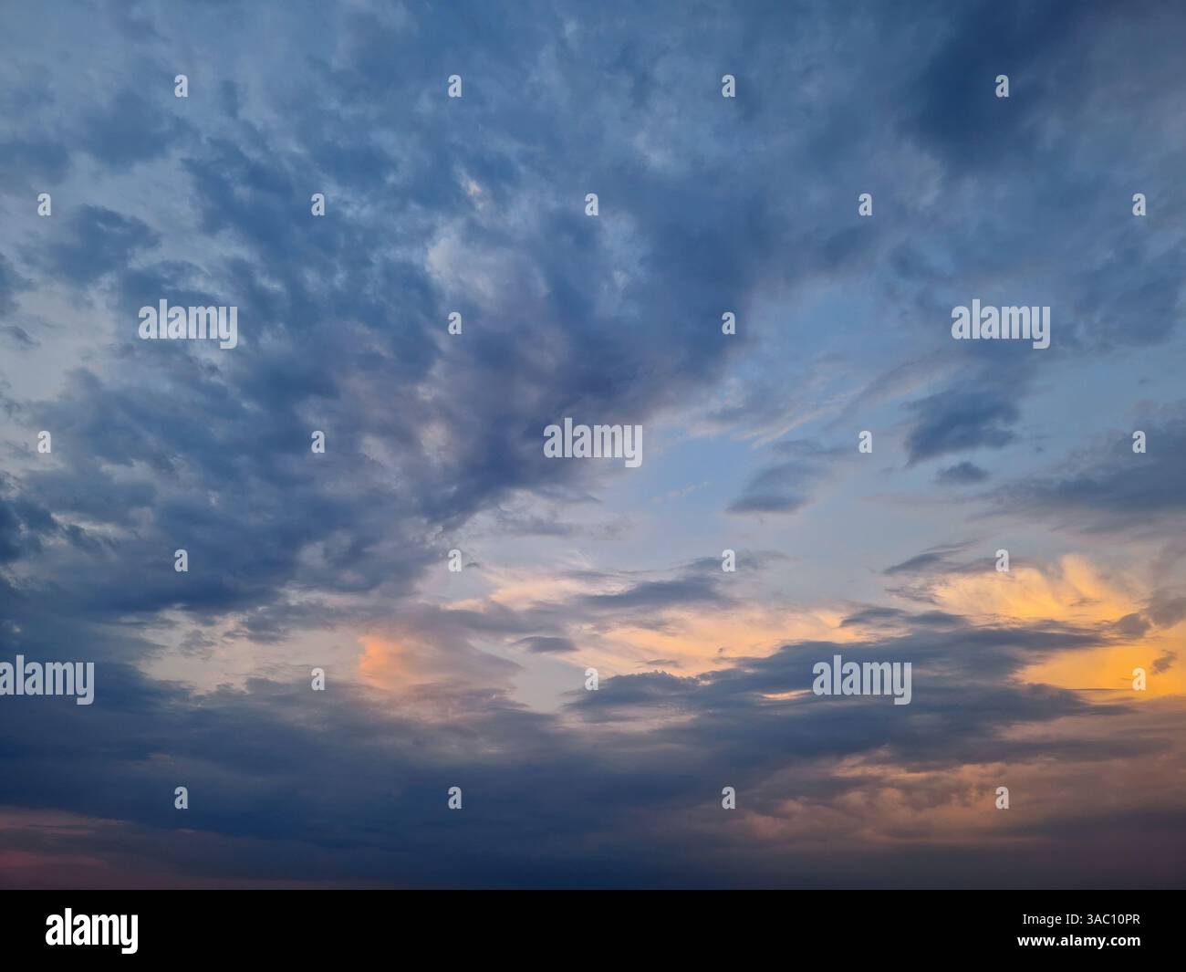 A vast sky view with dynamic clouds formation, hues of blue and subtle orange at the horizon, suggesting either sunrise or sunset. The interplay of li - Smartphone Captured Stock Image