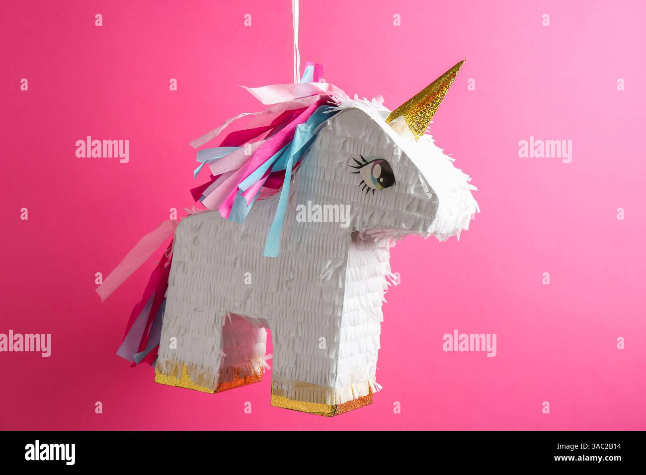 Bright pinata in shape of unicorn hanging on pink background Stock ...