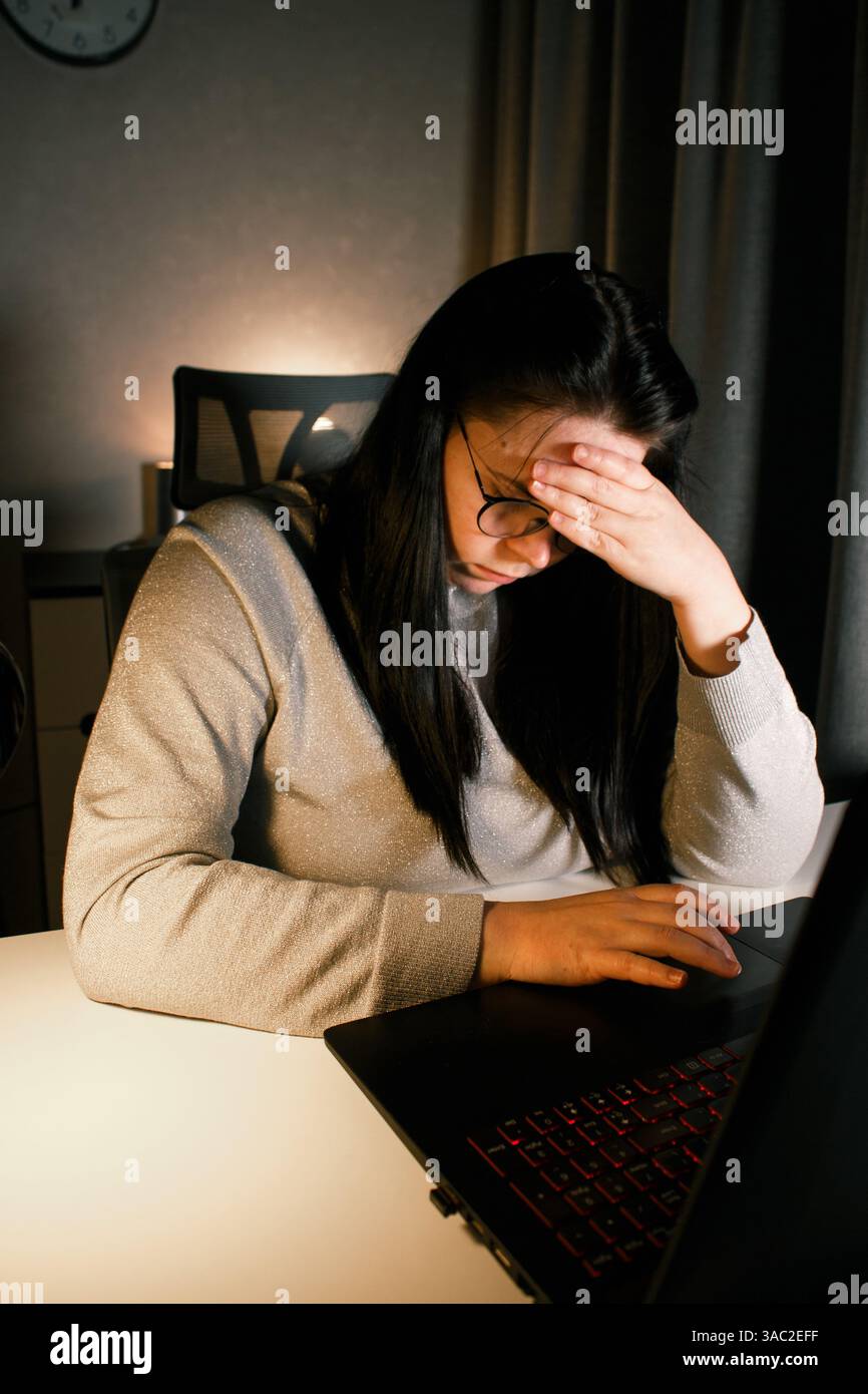 Tired woman working on computer touching her head because of headache ...