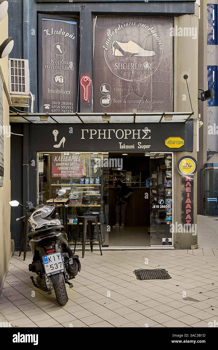 Crete.Greece - april 03, 2025: Exterior view of a shoe repair shop with colorful signs offering cobbler services, key duplication, and immobilizer rep Stock Photo