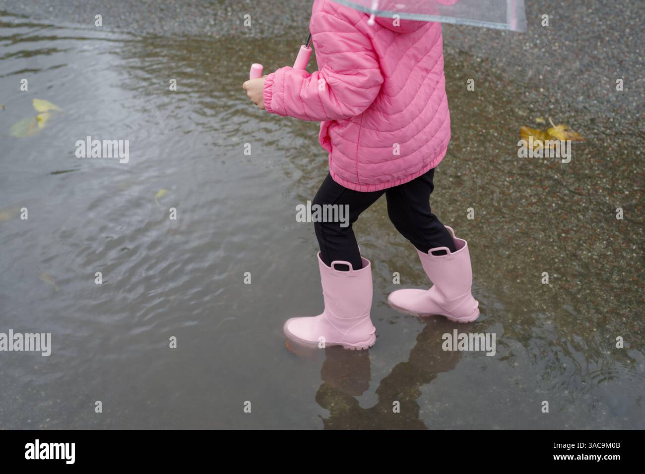 Girl playing in a puddle of water after rain Stock Photo - Alamy