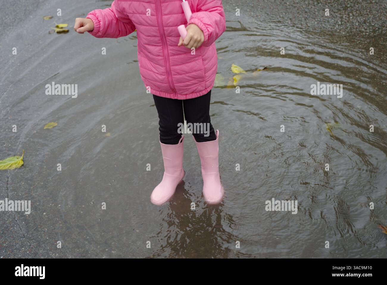Girl playing in a puddle of water after rain Stock Photo - Alamy