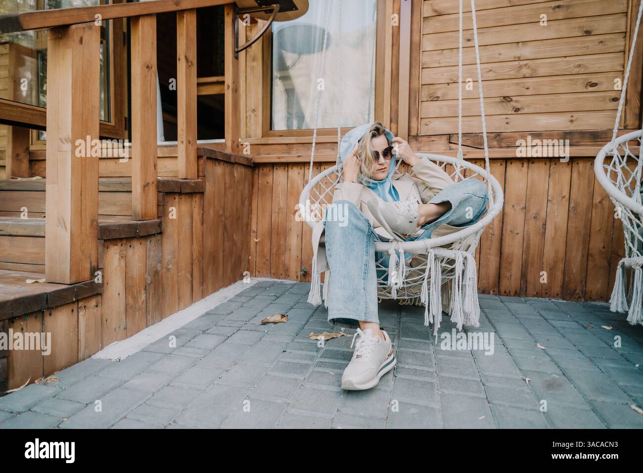 Woman Relaxing in a Hanging Chair on a Wooden Porch Stock Photo - Alamy