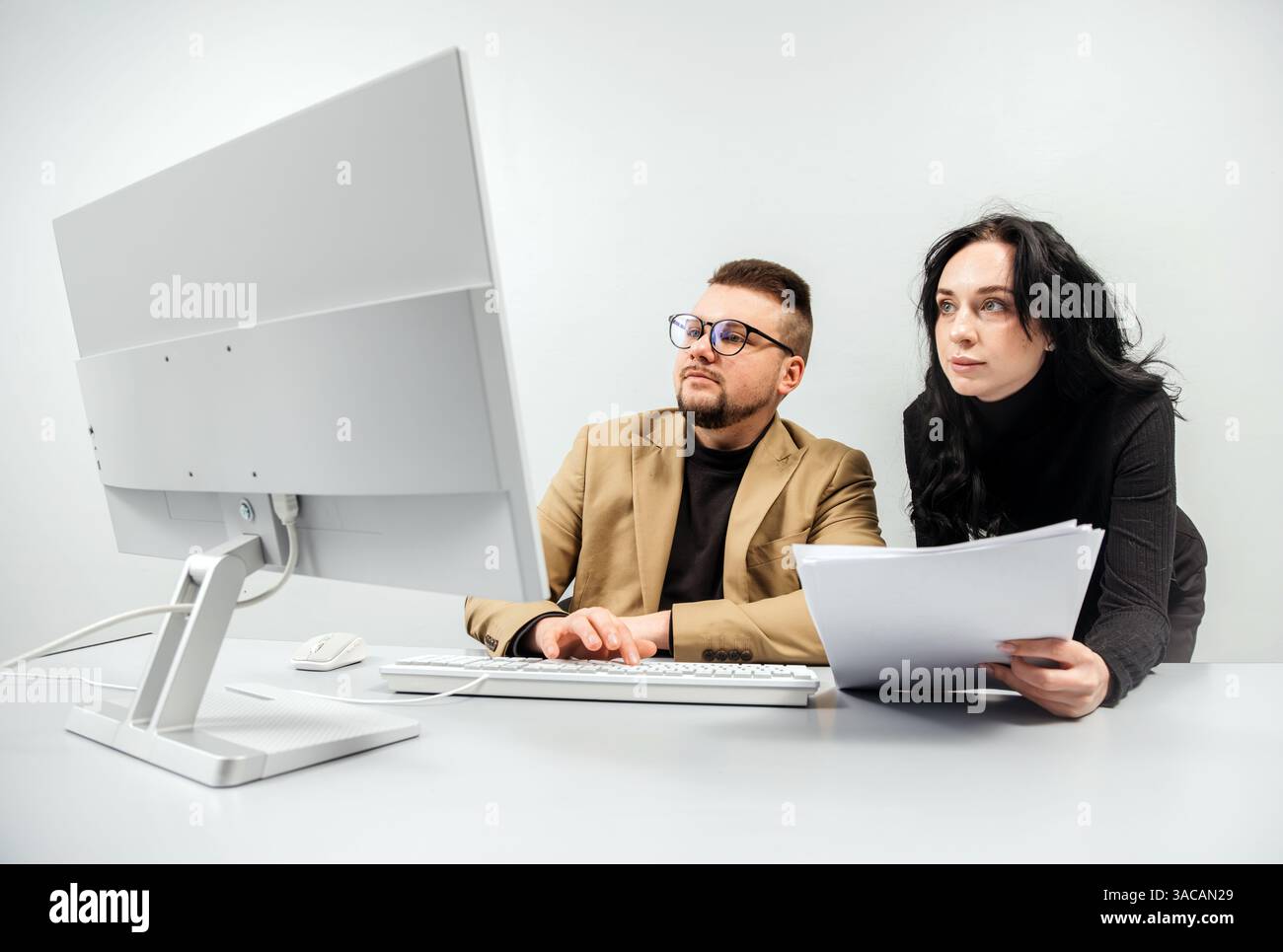 Two versatile business analysts discussing data management using a laptop. Concept consulting, training Stock Photo