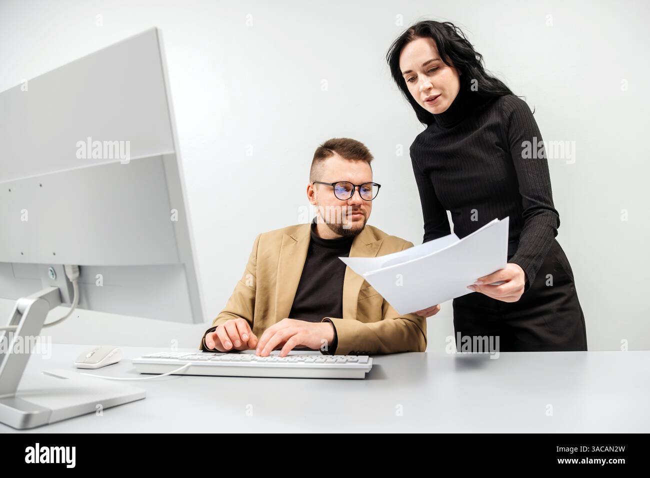 Two versatile business analysts discussing data management using a laptop. Concept consulting, training Stock Photo