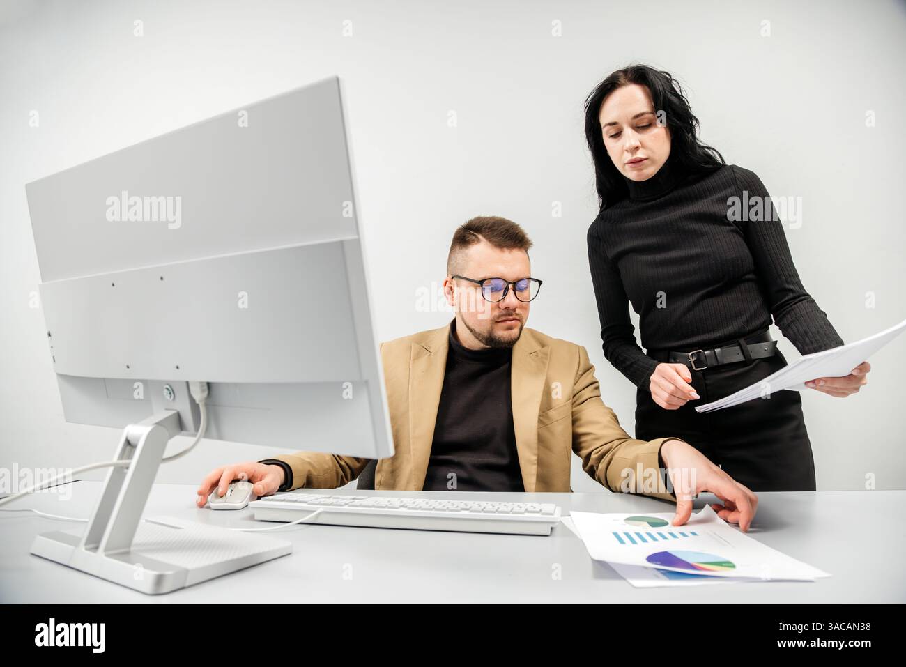 Two versatile business analysts discussing data management using a laptop. Concept consulting, training Stock Photo