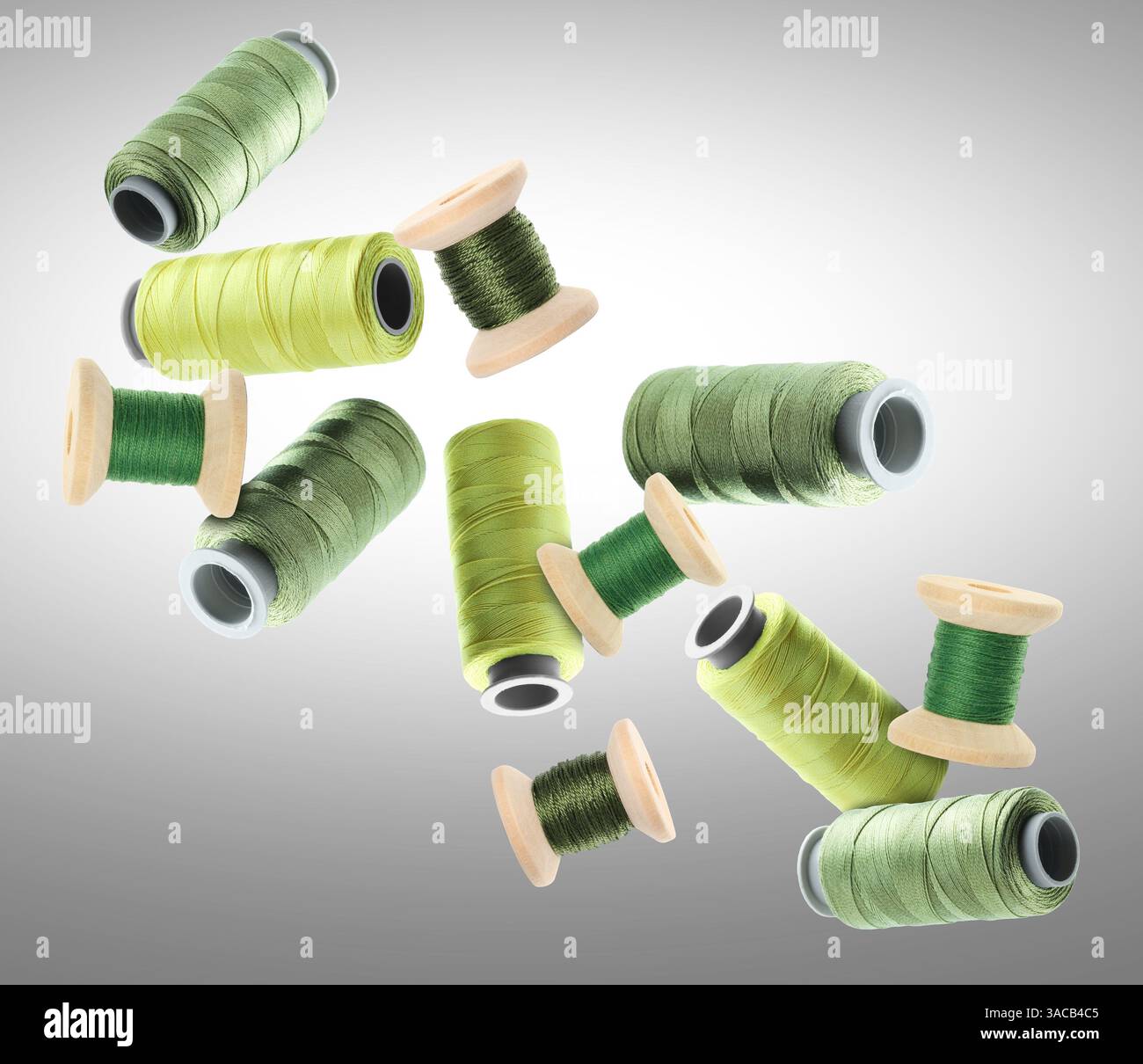 Many sewing threads in different shades of green flying on grey ...