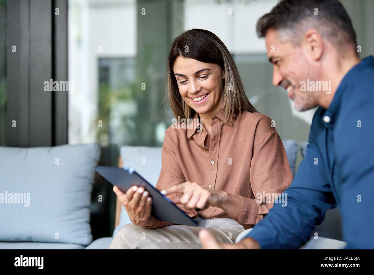 Two happy professional business executives talking using tablet in office. Stock Photo