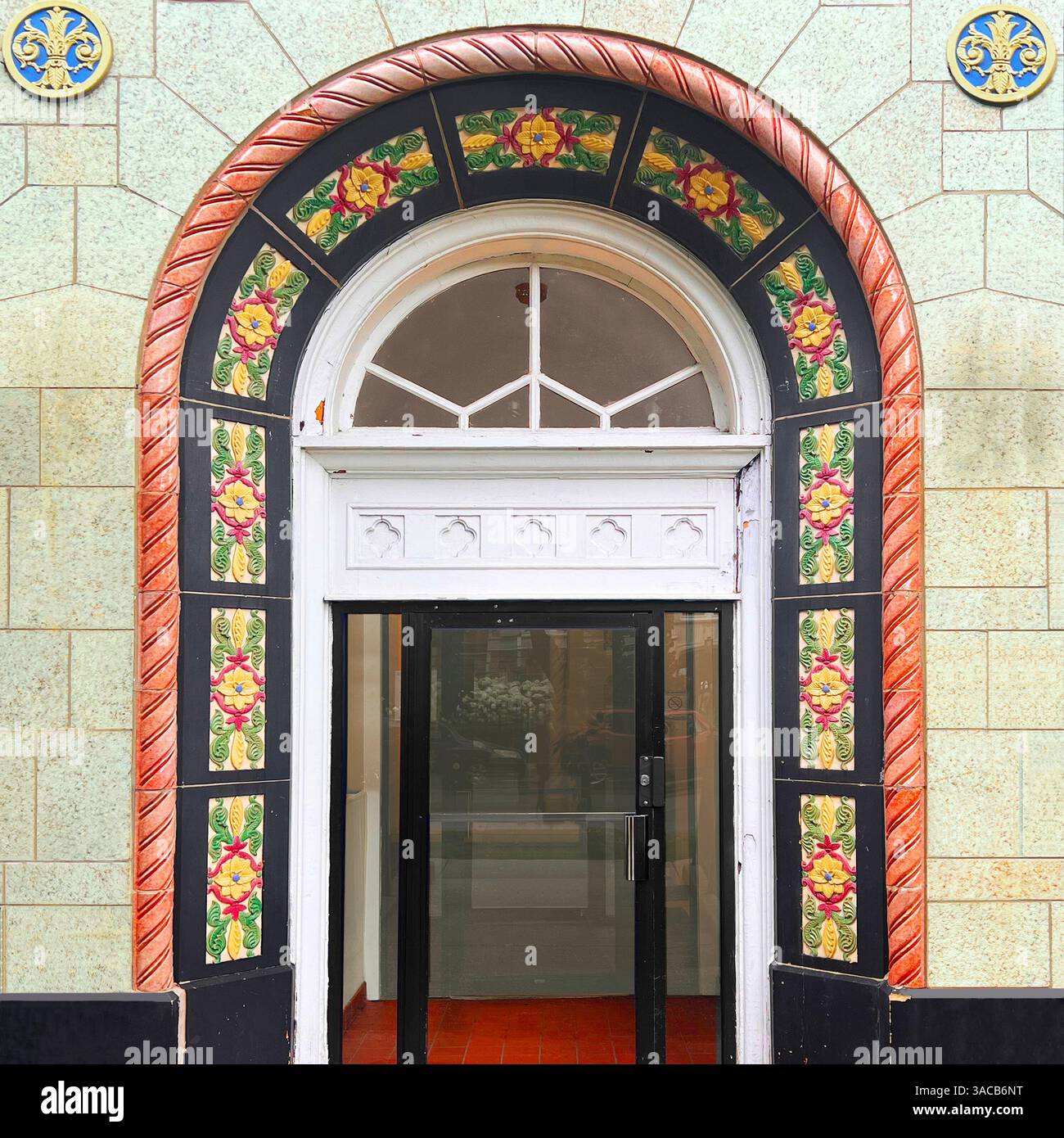 A colorful arched entryway framed by floral glazed tiles and bold terracotta trim highlights historic building facade in Chicago. - Smartphone Captured Stock Image