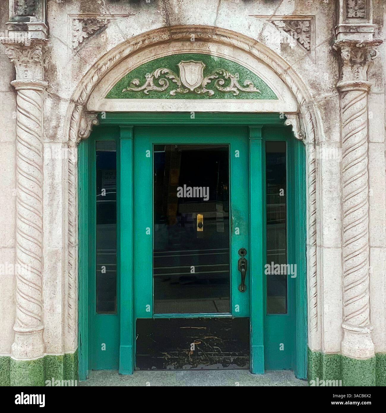 A vivid green door framed by ornate stone columns and an arched pediment with decorative scrollwork and shield motif. - Smartphone Captured Stock Image