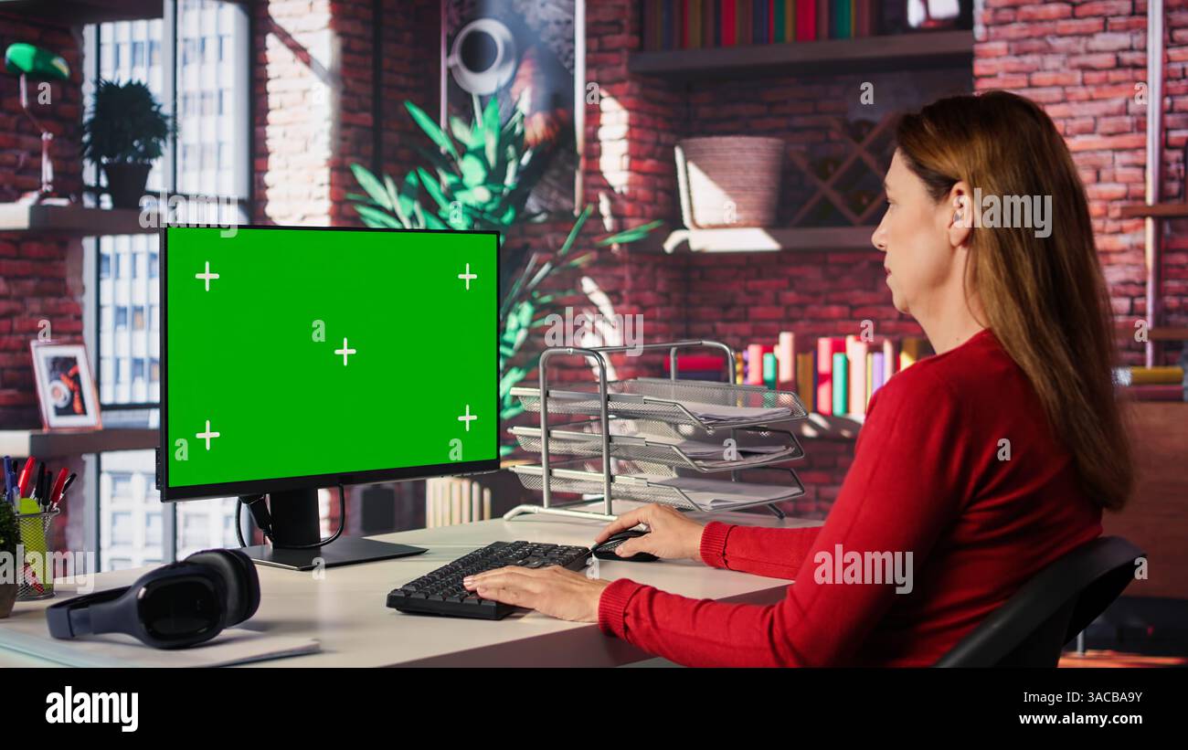 Adult woman typing on pc with chroma key screen at her loft desk ...