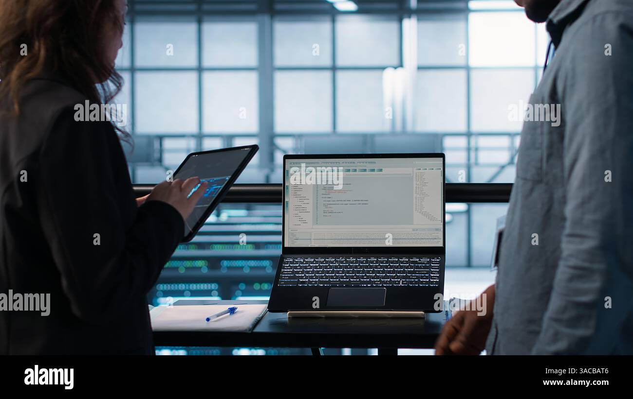 Programmers using AI technology on laptop and tablet in data center employing machine learning models. Devices used by artificial intelligence IT experts in server farm, camera A Stock Photo