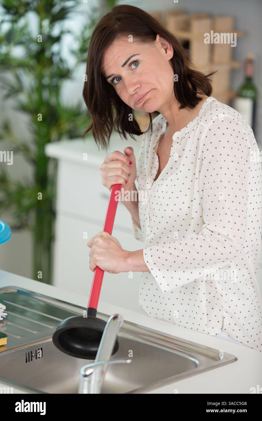 woman is trying to unblock the sink Stock Photo