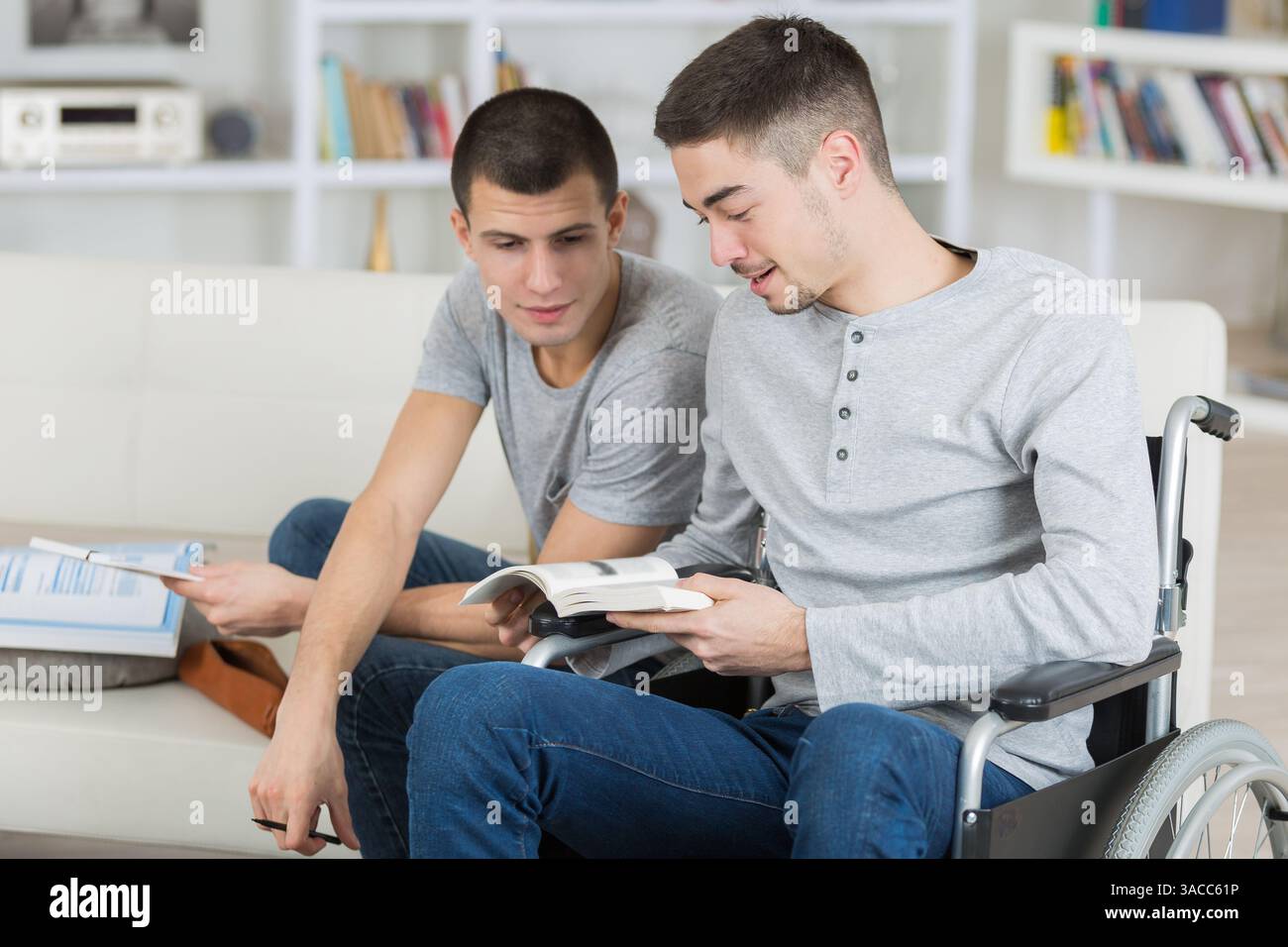 two male students one in wheelchair doing homework Stock Photo