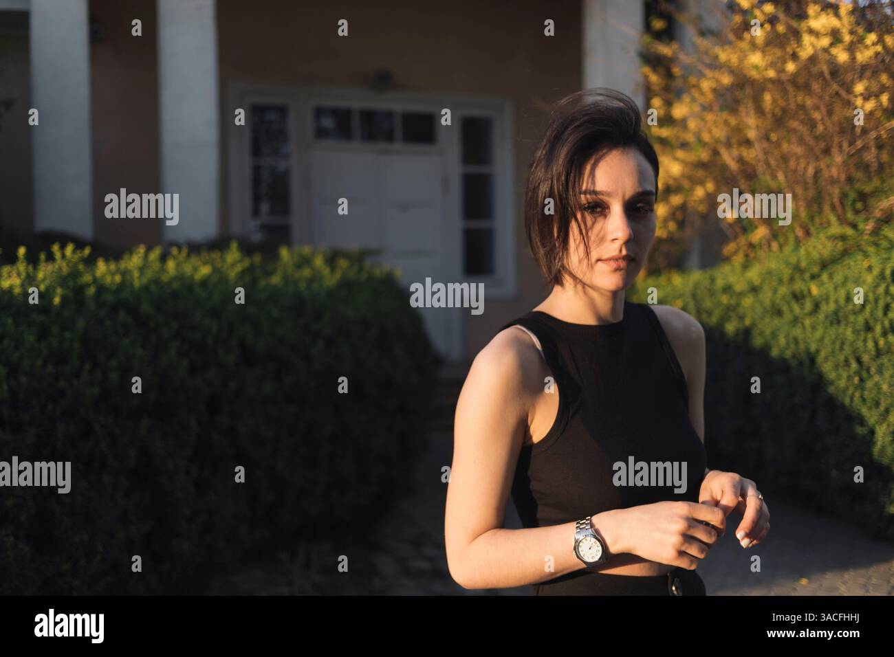 Stylish Young Woman in Black Outfit Standing Outdoors Stock Photo